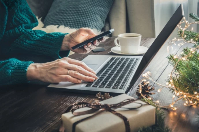 Woman with iphone in hand and on laptop